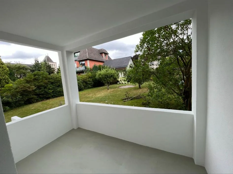 Innenseite einer frisch gestrichenen weißen Loggia mit Blick in den Garten.