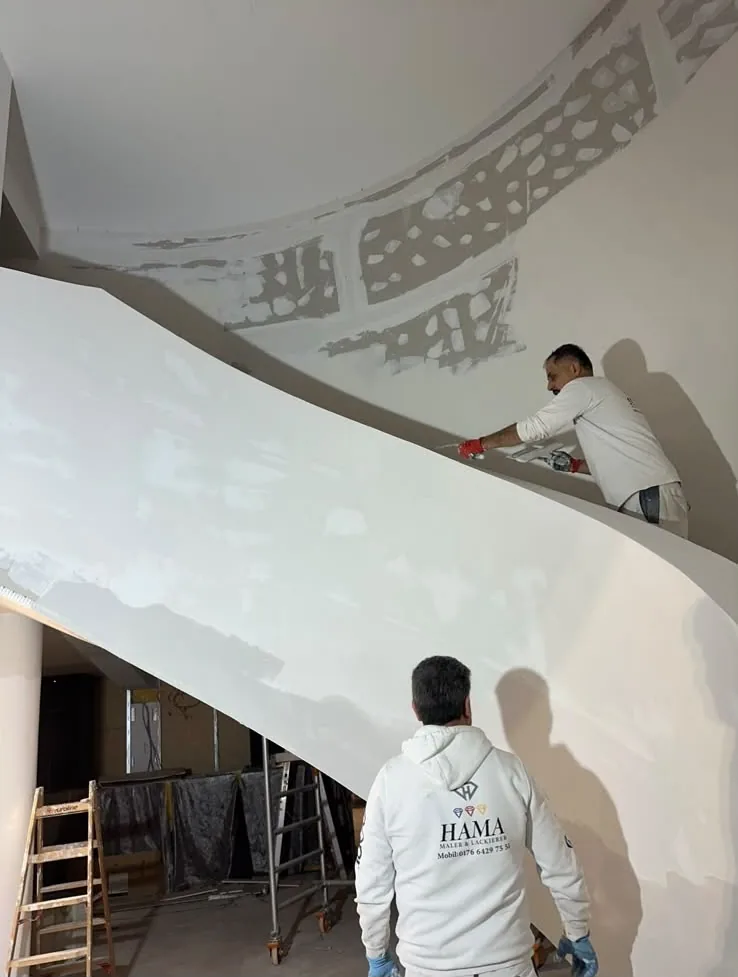 Zwei Maler von HAMA spachteln die geschwungene Untersicht einer großen Treppe.