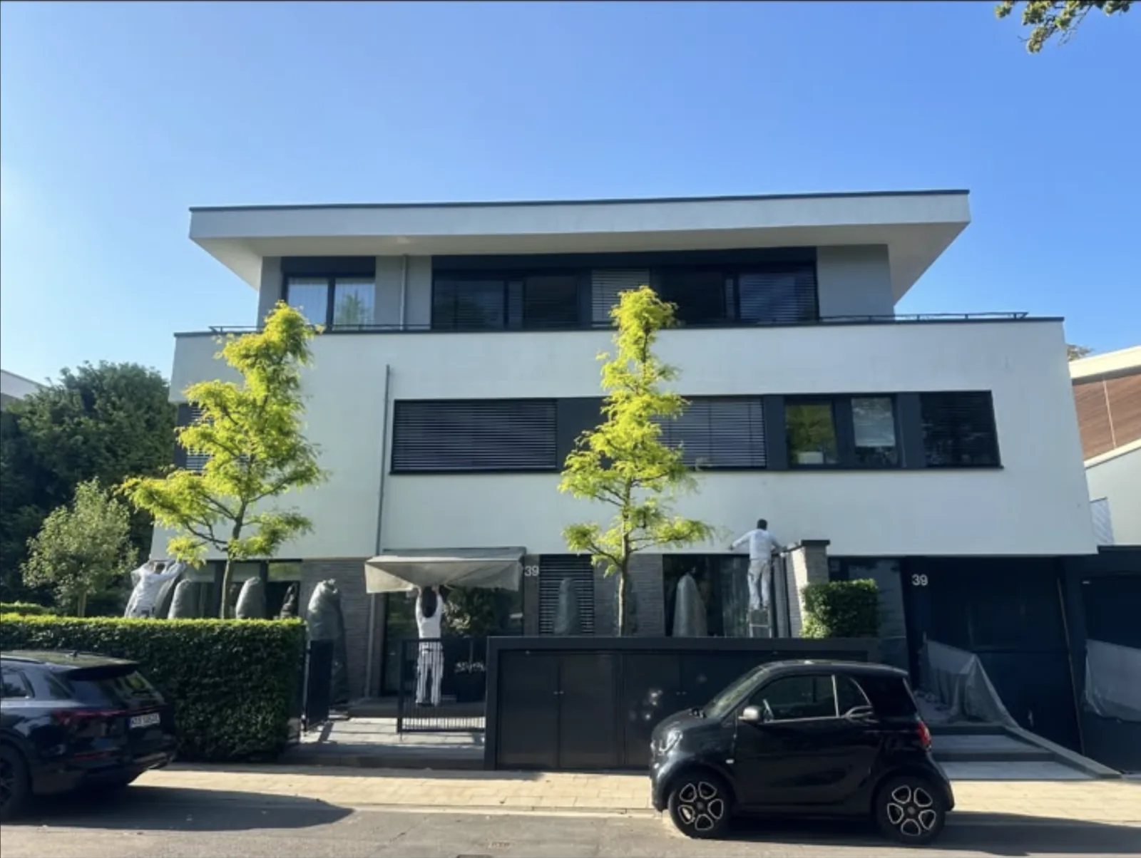 Maler von HAMA streichen die Fassade einer modernen weißen Stadtvilla mit Flachdach in Köln.